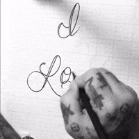 Illustrated gif. Tattooed hand sketches out very scrolly text on graph paper. Text, “I love you.”