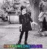 TV gif. In black and white, Wednesday Addams from the original Addams Family dances in her house. She has a happy, but concentrated look on her face as she does a little two step and wiggle of the arms. The rainbow flashing text at the bottom says, “Happy Wednesday!!” 