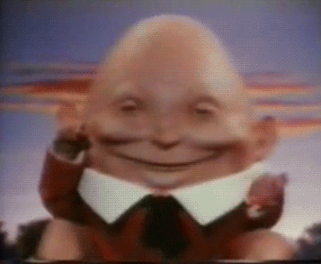 Video gif. Humpty Dumpty Puppet sits on a stone wall. He puts his arms up and smile, and then falls backwards, behind the wall.