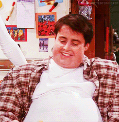 Friends gif. Matt LeBlanc as Joey Tribbiani wears a fat suit and smiles hungrily at the piece of chicken he lifts on a fork.