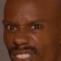 Video gif. A close-up of a man's face, sneering and frowning as if he's suspicious.