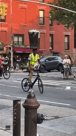 Man Balances Trashcan Atop Head While Cycling 