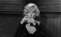 Movie gif. Marilyn Monroe as Sugar Kane in "Some Like It Hot," lazily closes her eyelids as she tips her head back to drink from a flask.