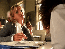 Music video gif. From "Baby one more time": Britney Spears sits behind a school desk and rests her head heavily on her hand as she fiddles impatiently with a pencil in the other. 