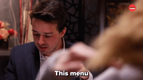 A man is looking at the menu and saying the words, "This menu is a lot more expensive than I expected."