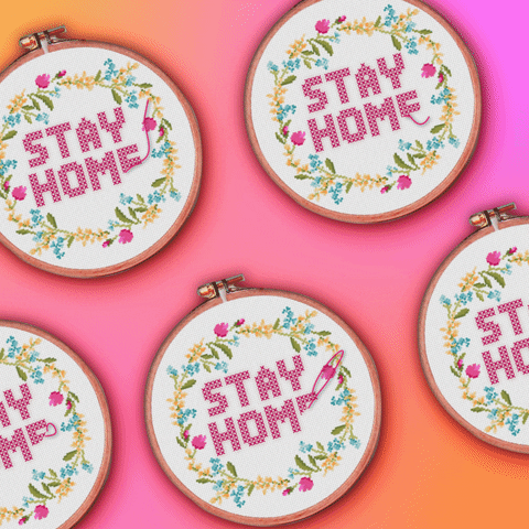 Digital art gif. Against a vibrant, blended pink and orange background, five embroidery hoops decorated with a wreath of flowers wiggle while a needle actively embroiders text reading, "Stay home" in pink lettering.
