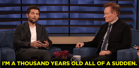 TV gif. Adam Scott is being interviewed by Conan O' Brien on Conan. Adam looks up from his phone and says, "I'm a thousand years old all of a sudden."