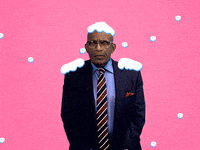 Reaction gif. Al Roker in a navy blue suit with cartoon snow falling around him and building up on his shoulders and on top of his head. He gives an exaggerated shiver to pretend that he’s cold from the snow.