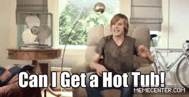 Video gif. A man sitting in an armchair yells out, "Can I get a hot tub!" and a hot tub suddenly appears in his living room.