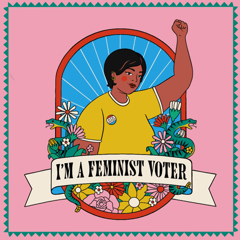 Digital art gif. Woman wearing an “I voted” sticker pumps her fist in the air against a pink background. She is flanked by colorful flowers and two hissing rattlesnakes, along with a banner below her that reads, “I’m a feminist voter.”