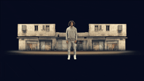 Celebrity gif. Daveed Diggs stands in front of a home that blows up and a huge plume of fire explodes over him.