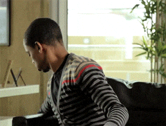 Video gif. A teen boy grabs some popcorn before settling into his couch to watch something--drama, perhaps?