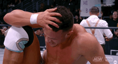 Sports gif. Wrestler Ricky Starks crouches down in the ring, looking like he's in pain, taking a moment to catch his breath.