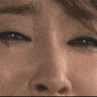Video gif. We see a up close shot of a woman's eye before panning out to see her sobbing face.