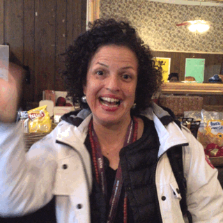 Celebrity gif. Filmmaker Michele Stephenson waves at us enthusiastically.