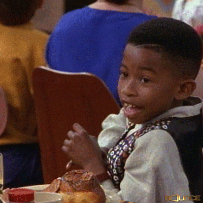 TV gif. A scene from Moesha. During a lively banquet, a child in a colorful vest turns to the side. He bounces his shoulders, makes finger guns, and smiles.