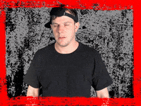 Video gif. Kyle Gordon, a YouTuber, pops his chest and squints his eyes as he scans the room. 