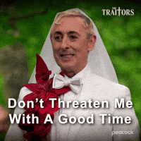Sponsored gif. Traitors host Alan Cumming says, “Don't threaten me with a good time.” He wears a white suit with red flowers pinned to the left side and a white wedding veil. Text also reads, “Don't threaten me with a good time.”