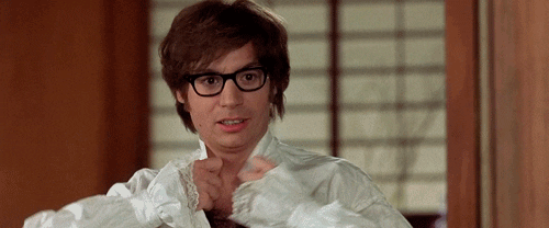 Movie gif. Gazing seductively, Mike Myers as Austin Powers rips open his shirt to reveal a very hairy chest.