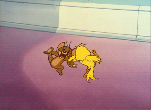 Cartoon-gif.  Jerry de bruine muis danst opgewonden arm in arm met Quacker, een gele vogel.  Ze trappen met hun benen terwijl ze in een cirkel dansen.