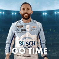 Sponsored gif. NASCAR driver Ross Chastain rubs his hands together and looks from side to side in anticipation. He wears a driver fire suit decorated with many sponsor logos with the largest being the Busch Light beer logo across the center of his abdomen. Text reads, “Go time.”