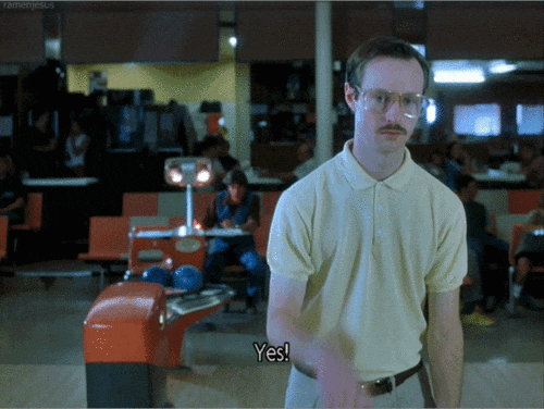 Movie gif. Aaron Ruell as Kip Dynamite in Napoleon Dynamite is in a bowling alley. He closes his eyes and pumps his fist down as he says, “yes!” as if trying to be cool with his excitement.
