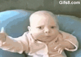 Video gif. Baby frowns and looks at us intensely, waving his arm toward him mysteriously, then smiles.