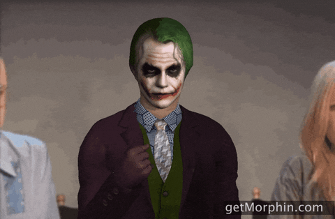 Video gif. Using a Joker filter that makes the person look like Joker in both face and clothing, a person throws confetti.