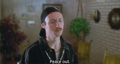 Movie gif. Aaron Ruell as Kip in Napoleon Dynamite wears a durag and a gold chain as he holds up a peace sign and says, "Peace out," then turns to walk away.