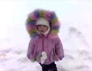 Video gif. Child wearing a purple winter coat falls backward into the snow.