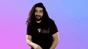 Celebrity gif. Andy Anaya covers his mouth his hand cheekily. Text reads, "Oops," all against a purple to blue gradient background.