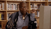 TV gif. Sitting at a computer in a library, Tituss Burgess in Unbreakable Kimmy Schmidt bats his eyes then looks away in boredom.