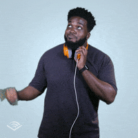 Video gif. A friendly young man, headphones around his neck, points to something above him with a declarative nod.