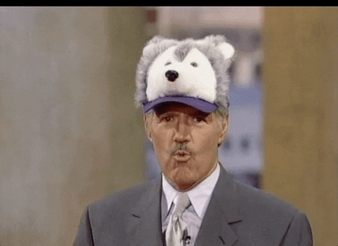 TV gif. Alex Trebek from Jeopardy, wearing a hat that resembles a fuzzy wolf, says "woof."
