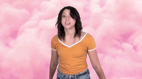 Celebrity gif. Katie Molinaro stands in front of a pink cloud background and looks eager while pointing at us with both hands and saying, "Yes!"