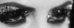 Video gif. In black and white, a woman with sparkling, bejeweled lids bats her eyes.