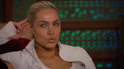 Reality TV gif. Blonde contestant on The Bachelor with her fingers behind her head and her eyes darting left and light, pondering or scheming.