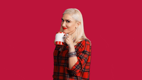 Celebrity gif. Gwen Stefani sips a mug of tea against a red background and nods at us in acknowledgment.