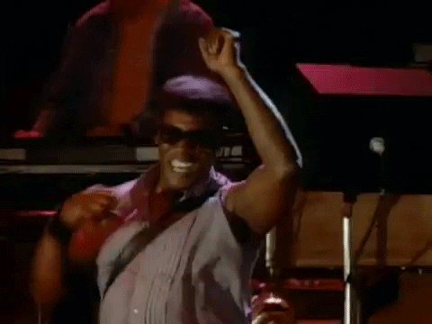 Celebrity gif. Performing onstage, Clarence Clemons smiles and dances, clapping his hands above his head, with his sax slung over his shoulder.
