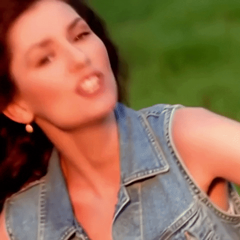 Music video gif. Shania Twain in the Any Man of Mine music video looks at us as she tilts her head towards us. She sings out, “yeahhhh”