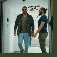TV gif. Demet Ozdemir on Daydreamer walks through a door with a swagger in his walk. People stare at him as he walks through the door and he waves his hands up in the air. He has a cool expression on his face that’s hidden behind his dark sunglasses. Text, “Daydreamer. 14.45 Canale 5.”