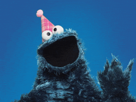Sesame Street gif. Cookie Monster, wearing a pink party hat, dances around and waves his arms in excitement.