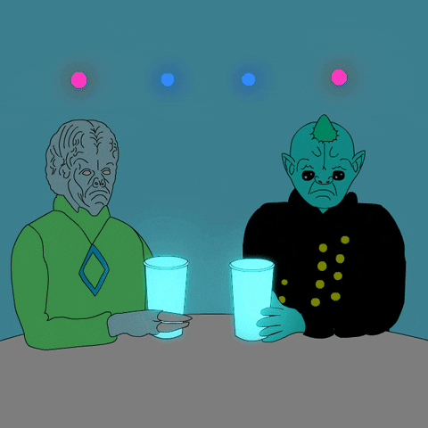 Illustrated gif. Two frowning alien figures sit at a table and raise and clink their glasses to cheers.