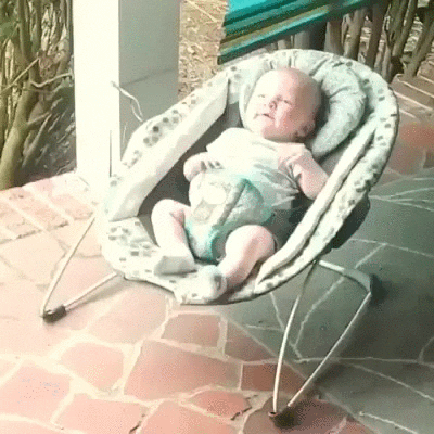 Video gif. Dalmatian puppy crawls up onto a bouncy seat where a baby lies buckled in, and nestles in next to the baby.