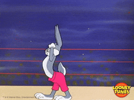 Cartoon gif. Bugs Bunny is in a wrestling ring and he's walking around shirtless with pink shorts and his chest puffed up and arms flexed.
