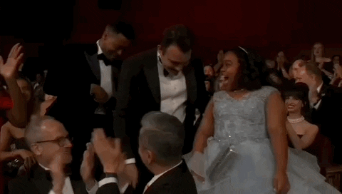 Oscars 2024 GIF. Porche Brinker of The Last Repair Shop, excitedly lifts her gown to descend the stairs and accept the Oscar.