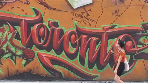 A GIF of a person walking past a graffiti art that spells "Toronto".