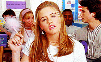 Movie gif. Alicia Silverstone as Cher in Clueless stares pensively into space, lost in thought, fluffy pen in hand.