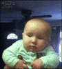Video gif. Man holding a baby under the arms gives the baby a big cheek kiss, and then the baby sticks out his lower lip, appearing sad.