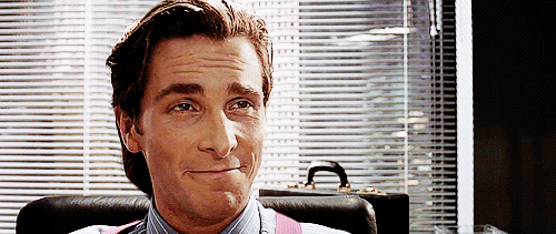 Movie gif. Christian Bale as Patrick Bateman in American Psycho sits in his office. He has an insincere smile on his face as he says, “Thanks,” and his face rests into a stern expression. 